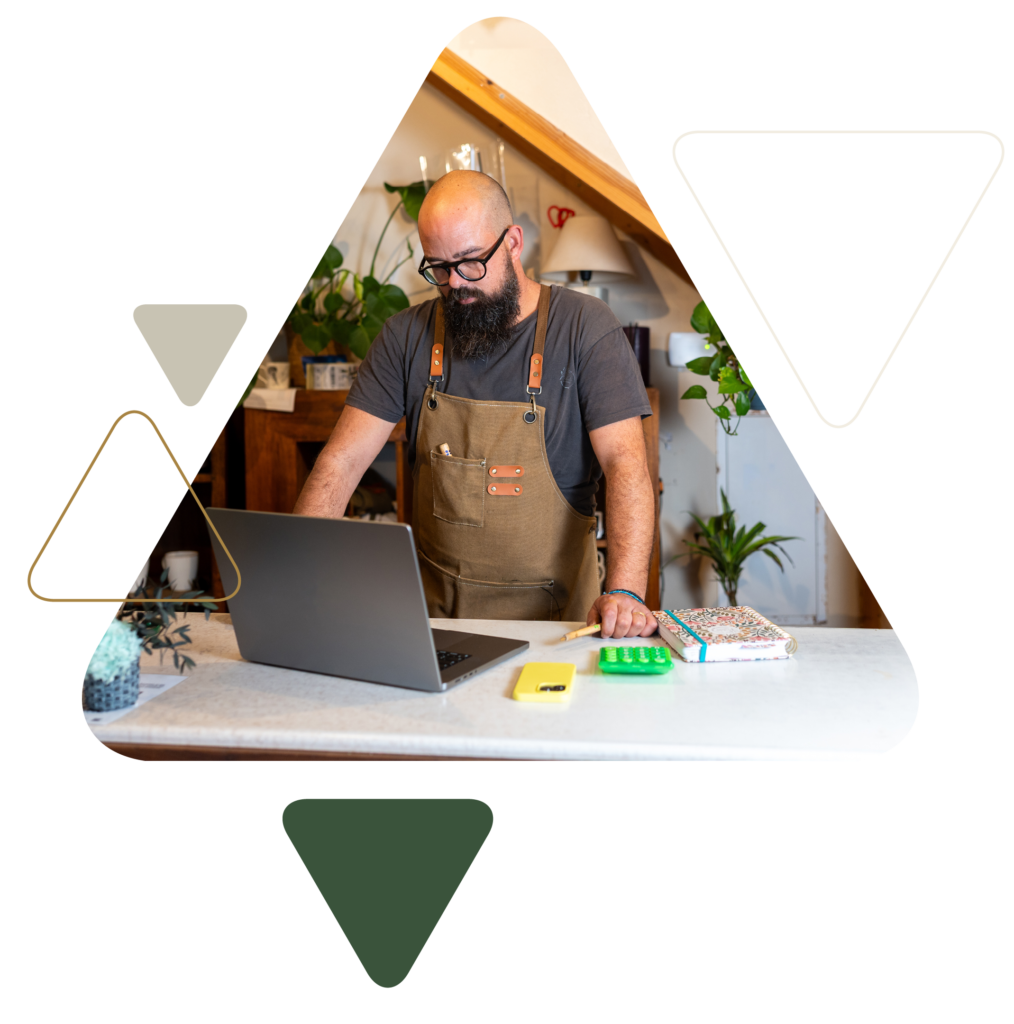 Bearded man in apron working on laptop indoors