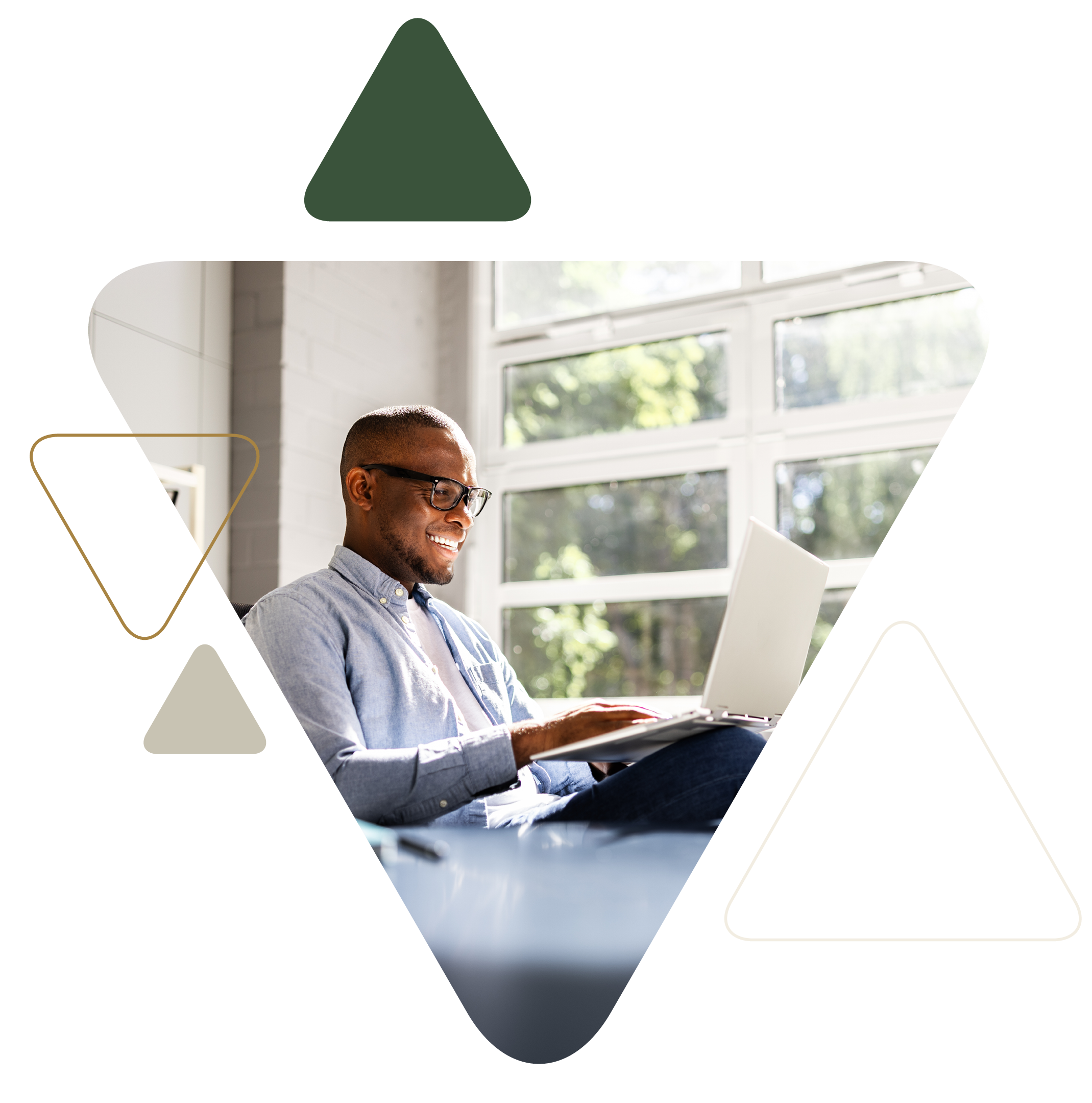 Man smiling while using laptop by window